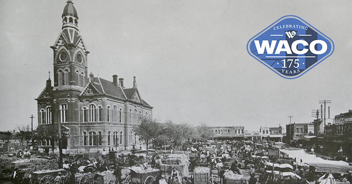 Black and white photo of old Waco City Hall with a clock tower and cars parked in the town square