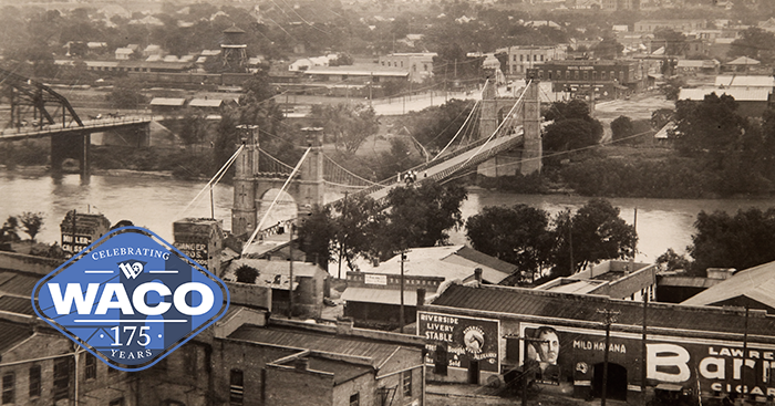 Sepia photo with an aerial view of the Suspension Bridge with a train crossing parallel to the river.