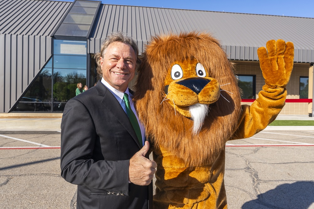 Mayor Jim Holmes holding a thumbs up next to a lion mascot