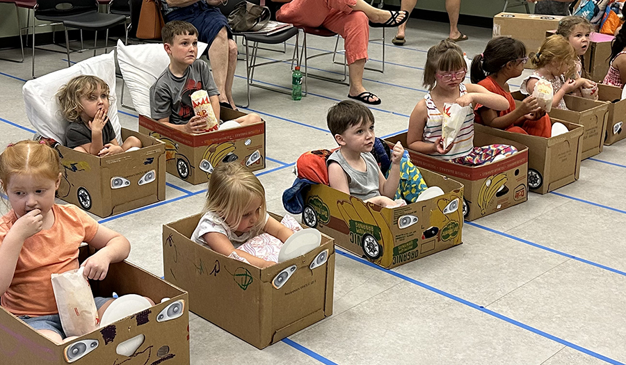 Kids sitting in card board box cars for a movie.