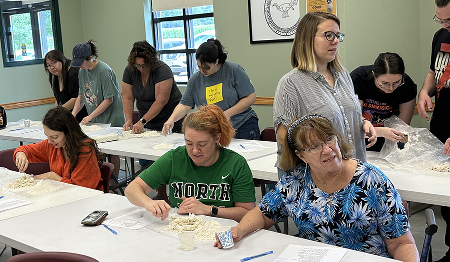 Adults learning how to make bread in a classroom.