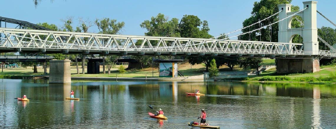 Waco Suspension Bridge and paddlers on river.