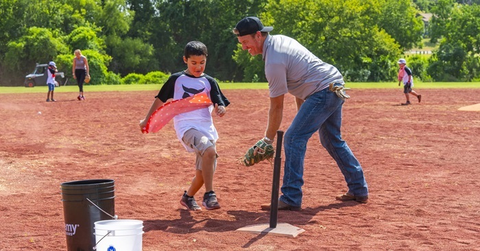 Chip Gaines playing baseball with a kid on a dirt field